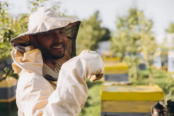 Szczęśliwy Uśmiechnięty Indyjski Pszczelarz Mundurze Stojący Pasiece Trzymający Pszczoły Farmie — Zdjęcie stockowe