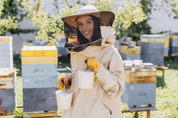 Happy smiling female beekeeper holding ready organic honey made in bee farm