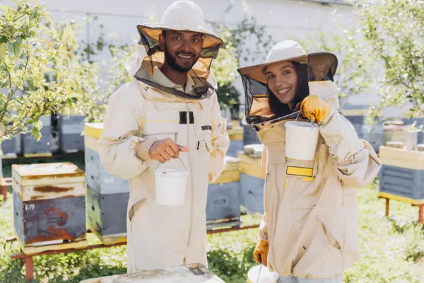 Szczęśliwa Uśmiechnięta Międzynarodowa Para Pszczelarzy Trzyma Gotowy Organiczny Miód Wyprodukowany — Zdjęcie stockowe