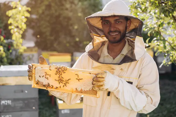 Szczęśliwy Uśmiechnięty Indyjski Pszczelarz Mundurze Stojący Pasiece Trzymający Ramę Pszczoły — Zdjęcie stockowe