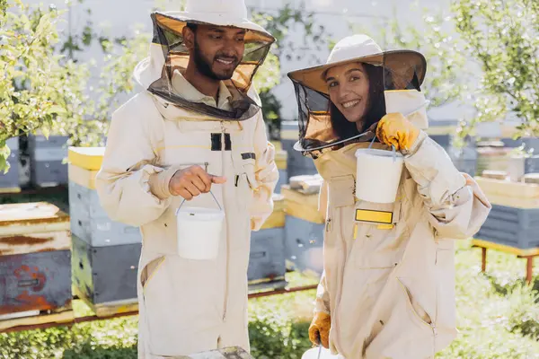 Szczęśliwa Uśmiechnięta Międzynarodowa Para Pszczelarzy Trzyma Gotowy Organiczny Miód Wyprodukowany — Zdjęcie stockowe