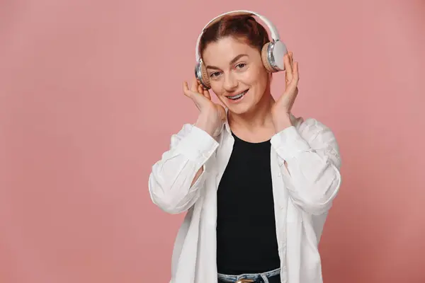 Сучасна Жінка Посміхається Брекетами Зубах Слухає Музику Навушниках Рожевому Фоні Стокове Фото