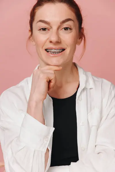 Moderne Glückliche Frau Zeigt Lächeln Mit Zahnspange Auf Rosa Hintergrund lizenzfreie Stockfotos