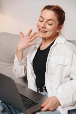 Diş teli takan olgun bir kadın video konferansında ortodontistle görüşüyor.