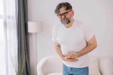 Evde sindirim sorunları, karaciğer ve safra kesesi sorunları ve bağırsak ağrısı çeken yaşlı bir adam var.