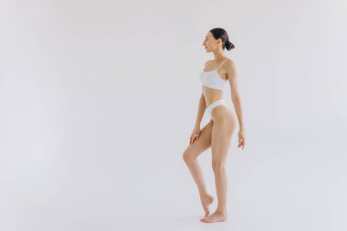 İnce vücutlu, beyaz stüdyo arka planında fotokopi aletiyle poz veren güzel bir kadının tam boy portresi.