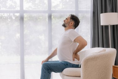 Evdeki kanepede sırt ağrısı çeken son sınıf öğrencisi.