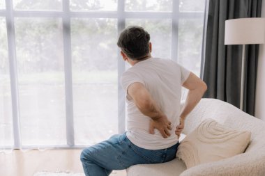 Evdeki kanepede sırt ağrısından muzdarip yaşlı adamın arka görüntüsü..