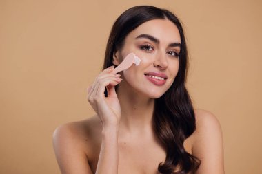 Yarı çıplak kadın, güzellik için yüz ve fırça kremi, kuaför ve cilt bakımı bej arka planda. Mutlu model, yüz losyonu ve dermatoloji, kolajen ve mutluluğun gülümsemesi için makyaj malzemesi.