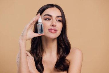 Bej arka planda Serum Bırakan Kadın. Pipette 'ten Serum Kolajeni Nemlendirici kullanan Avrupalı Kız. Yakın plan. Pozitif Gülen Güzel Kadın Portresi. Yüz Cildi Bakımı Konsepti