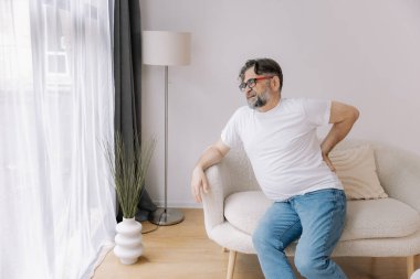 Evdeki kanepede sırt ağrısı çeken son sınıf öğrencisi.