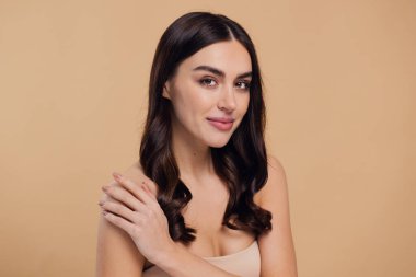 Güzel, genç, esmer, bej arkaplan, yüz bakımı, kozmetik, güzellik ve kaplıca, gülümseyen kadın portresi..