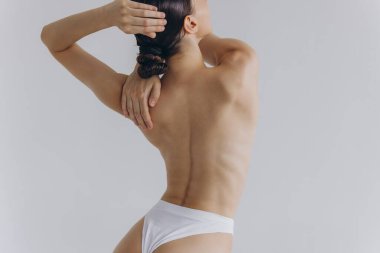 Arkadan kesilmiş, ince vücutlu, mükemmel ciltli, çıplak sütyen giyen seksi kadın beyaz arka planda izole edilmiş kalçalara el ele tutuşuyor. Yaşam tarzı diyet konsepti