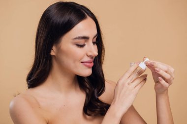 Bej arka planda Serum Bırakan Kadın. Pipette 'ten Serum Kolajeni Nemlendirici kullanan Avrupalı Kız. Yakın plan. Pozitif Gülen Güzel Kadın Portresi. Yüz Cildi Bakımı Konsepti