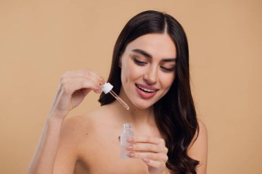 Bej arka planda Serum Bırakan Kadın. Pipette 'ten Serum Kolajeni Nemlendirici kullanan Avrupalı Kız. Yakın plan. Pozitif Gülen Güzel Kadın Portresi. Yüz Cildi Bakımı Konsepti