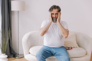 Ev, son sınıf öğrencisi ve stres, duygusal çatışma ve geçici baş dönmesi için kanepede baş ağrısı. Oturma odası, kanepe ve evde emeklilikten doğan acı, migren ve endişe içinde yaşlı bir adam.