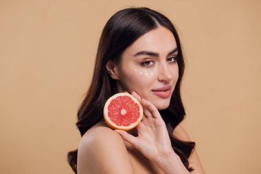 Göz Cildi Bakıcı Kadın. Greyfurt Tutan Güzel Genç Kadın Göz Altındaki Cilde Göz Kremi Döküyor. Antiyaj Tedavisi Konsepti. Yüksek Kalite