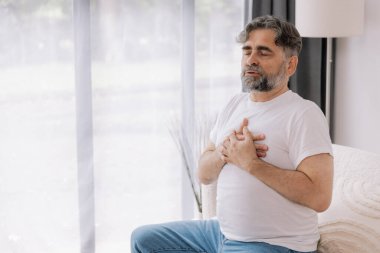 Kalp krizi, kalp krizi. Memnuniyetsiz orta yaşlı adam göğüs ağrısı çekiyor kalp krizi geçiriyor evde sağlık sorunları var. Yaşlı büyükbaba göğsüne dokunuyor ve damar tıkanıklığı yaşıyor.