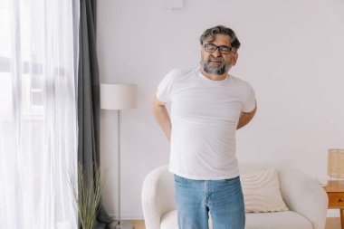 Hasta, mutsuz, yaşlı bir adam, kas hasarına dokunuyor. Sırtında ağrılar var. Evde sırt ağrısı. Fiziksel yaralanma ve sağlık sorunları