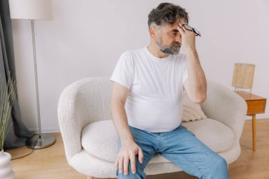 Ev, son sınıf öğrencisi ve stres, duygusal çatışma ve geçici baş dönmesi için kanepede baş ağrısı. Oturma odası, kanepe ve evde emeklilikten doğan acı, migren ve endişe içinde yaşlı bir adam.