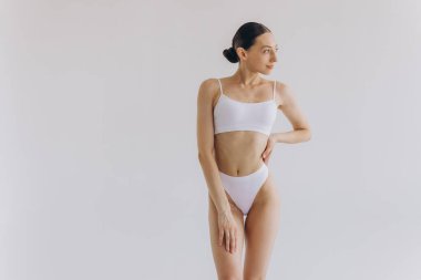 İnce vücutlu güzel bir kadının portresi. Beyaz stüdyo arka planında fotokopi alanı ile poz veriyor.