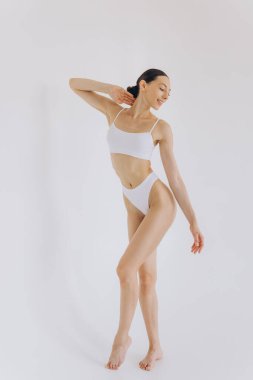 İnce vücutlu, beyaz stüdyo arka planında fotokopi aletiyle poz veren güzel bir kadının tam boy portresi.