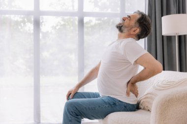 Evdeki kanepede sırt ağrısı çeken son sınıf öğrencisi.