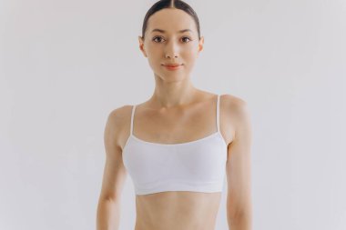 İnce vücutlu güzel bir kadının portresi. Beyaz stüdyo arka planında fotokopi alanı ile poz veriyor.