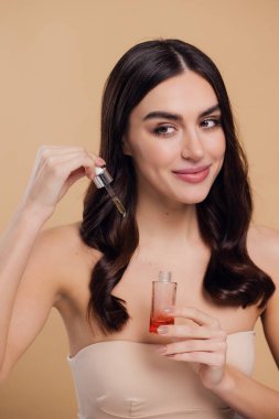 Bej arka planda saç köklerine gerekli yağı uygulayan mutlu genç kadının güzel portresi, metin için boşluk