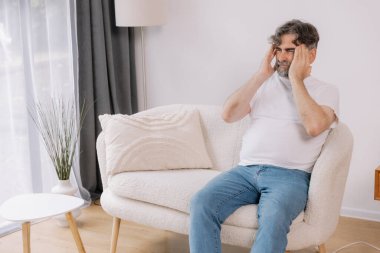 Ev, son sınıf öğrencisi ve stres, duygusal çatışma ve geçici baş dönmesi için kanepede baş ağrısı. Oturma odası, kanepe ve emeklilikten doğan acı, migren ve endişe içinde yaşlı bir adam. 