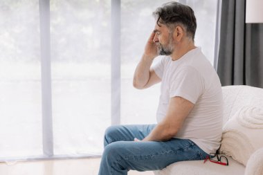 Ev, son sınıf öğrencisi ve stres, duygusal çatışma ve geçici baş dönmesi için kanepede baş ağrısı. Oturma odası, kanepe ve evde emeklilikten doğan acı, migren ve endişe içinde yaşlı bir adam.