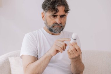 Gözlüklü kıdemli adam evde ilaç tarifini ve talimatlarını okur. Kişisel bakım konsepti, yaşlılar, kopyalama alanı.