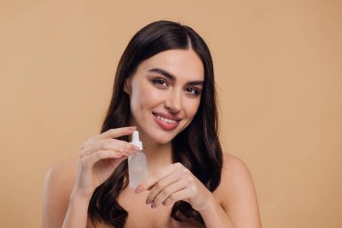 Bej arka planda Serum Bırakan Kadın. Pipette 'ten Serum Kolajeni Nemlendirici kullanan Avrupalı Kız. Yakın plan. Pozitif Gülen Güzel Kadın Portresi. Yüz Cildi Bakımı Konsepti