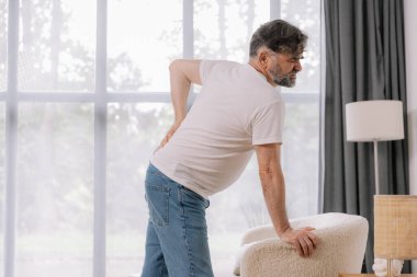 Evdeki kanepede sırt ağrısı çeken yaşlı bir adamın arka görüntüsü, reklamınız için yer açın.