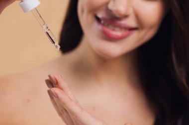 Bej arka planda Serum Bırakan Kadın. Pipette 'ten Serum Kolajeni Nemlendirici kullanan Avrupalı Kız. Yakın plan. Pozitif Gülen Güzel Kadın Portresi. Yüz Cildi Bakımı Konsepti