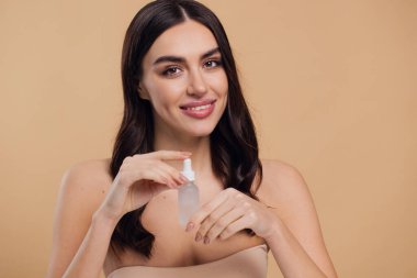 Bej arka planda Serum Bırakan Kadın. Pipette 'ten Serum Kolajeni Nemlendirici kullanan Avrupalı Kız. Yakın plan. Pozitif Gülen Güzel Kadın Portresi. Yüz Cildi Bakımı Konsepti