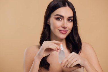 Bej arka planda Serum Bırakan Kadın. Pipette 'ten Serum Kolajeni Nemlendirici kullanan Avrupalı Kız. Yakın plan. Pozitif Gülen Güzel Kadın Portresi. Yüz Cildi Bakımı Konsepti