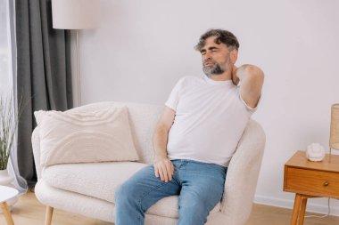 Üst sınıflardan biri içeride oturuyor, boynu ağrıyormuş gibi görünüyor. Üzüntülü bir ifadeyle boynunu tutuyor. Rahatsızlığını gösteriyor. Reklamınız için fotokopi odası.