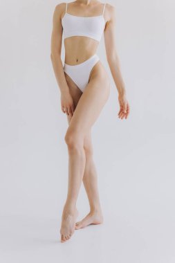 Manzarayı kapat. Beyaz stüdyo arka planında iç çamaşırlı, ince vücutlu güzel bir kadın.. 