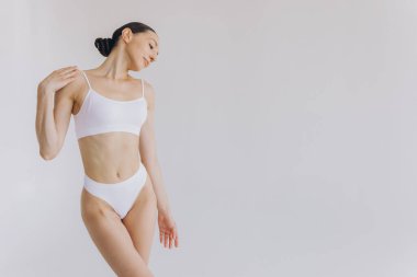 İnce vücutlu güzel bir kadının portresi. Beyaz stüdyo arka planında fotokopi alanı ile poz veriyor.