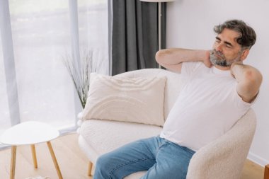 Üst sınıflardan biri içeride oturuyor, boynu ağrıyormuş gibi görünüyor. Üzüntülü bir ifadeyle boynunu tutuyor. Rahatsızlığını gösteriyor. Reklamınız için fotokopi odası.