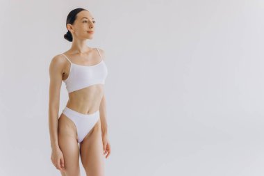 İnce vücutlu güzel bir kadının portresi. Beyaz stüdyo arka planında fotokopi alanı ile poz veriyor.