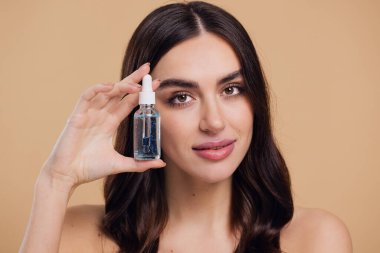 Bej arka planda Serum Bırakan Kadın. Pipette 'ten Serum Kolajeni Nemlendirici kullanan Avrupalı Kız. Yakın plan. Pozitif Gülen Güzel Kadın Portresi. Yüz Cildi Bakımı Konsepti