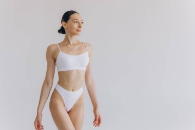 İnce vücutlu güzel bir kadının portresi. Beyaz stüdyo arka planında fotokopi alanı ile poz veriyor.