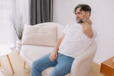 Üst sınıflardan biri içeride oturuyor, boynu ağrıyormuş gibi görünüyor. Üzüntülü bir ifadeyle boynunu tutuyor. Rahatsızlığını gösteriyor. Reklamınız için fotokopi odası.