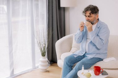 Yaşlı bir adamın mendile hapşırması, soğuk algınlığı veya alerjiden rahatsızlık duyması, mevsimsel alerjiler, virüs, grip ve hasta sağlığı, sağlık durumu, kıdemli bakım ve solunum için tıbbi tedavi