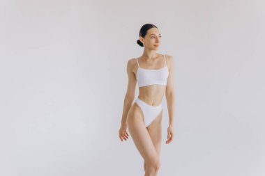 İnce vücutlu güzel bir kadının portresi. Beyaz stüdyo arka planında fotokopi alanı ile poz veriyor.