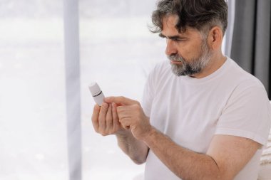 Gözlüklü kıdemli adam evde ilaç tarifini ve talimatlarını okur. Kişisel bakım konsepti, yaşlılar, kopyalama alanı.