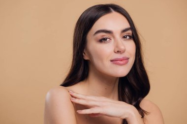 Güzel, genç, esmer, bej arkaplan, yüz bakımı, kozmetik, güzellik ve kaplıca, gülümseyen kadın portresi.