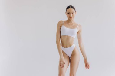 İnce vücutlu güzel bir kadının portresi. Beyaz stüdyo arka planında fotokopi alanı ile poz veriyor.